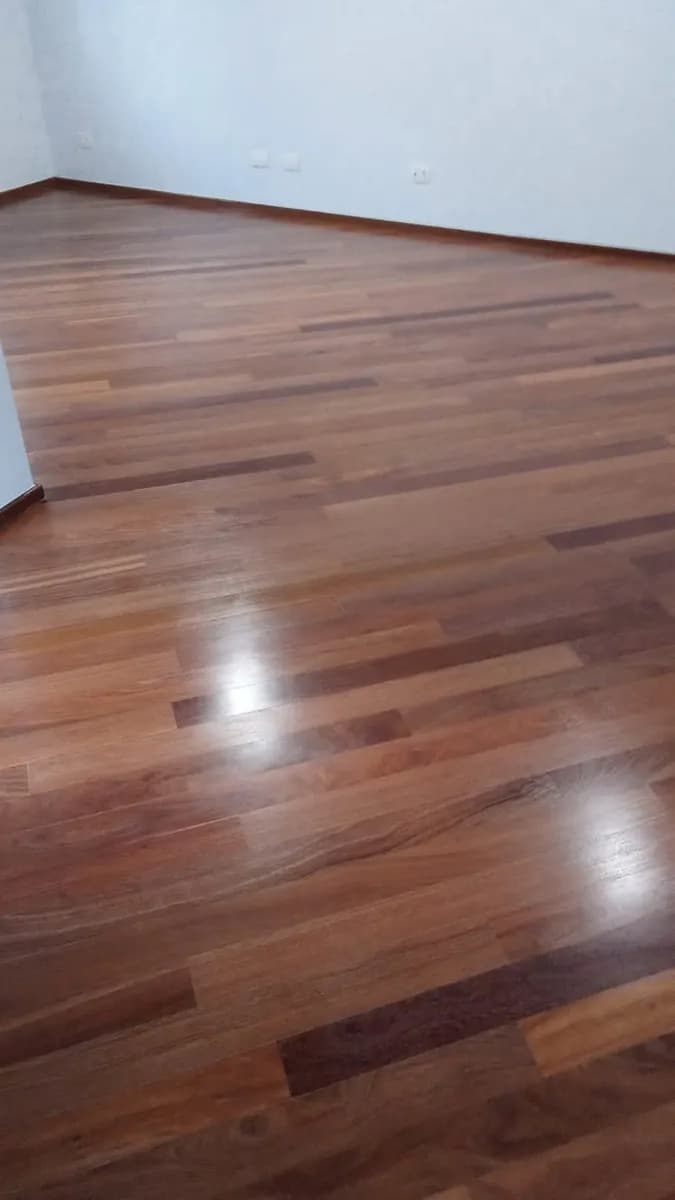 Assoalho de madeira escura com brilho intenso em quarto residencial