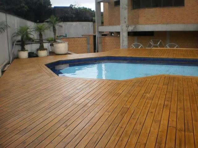 Deck de madeira instalado ao redor de piscina em residência
